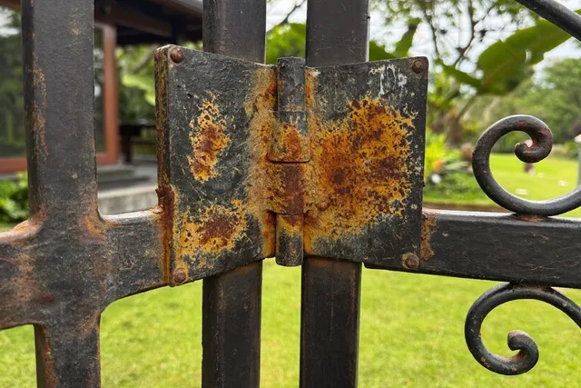 Rusted wrought iron villa gate hinge before anti-corrosion restoration in Bali